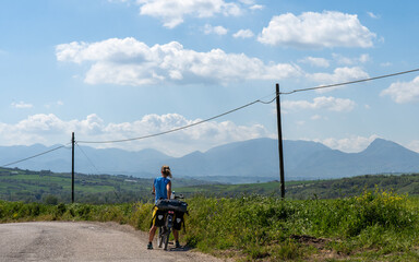 Cyclist pauses on a scenic road with mountains