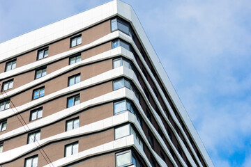 Fototapeta premium A modern residential building with a ventilated fiber cement façade and aluminum windows. The design features wavy lines, large windows, and a stylish and functional appearance.