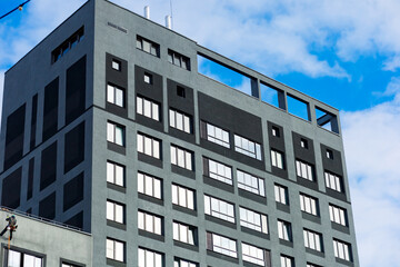 A modern building with a gray façade, rectangular windows, clean lines, and a minimalist design. Clean forms and simplicity create a sense of functionality and style.