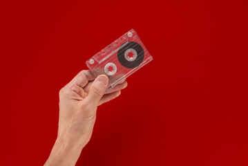 Man holding vintage old audio cassette with music of 90s. Audio cassette in hand, flat backdrop, open copy space. Perfect for retro-themed graphics