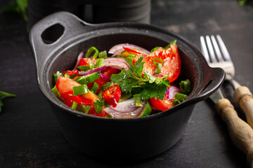 Fresh salad of tomatoes, cucumbers, chili peppers and onions in a rustic style