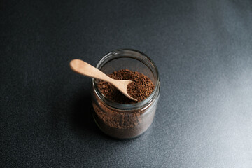 Instant coffee and spoon above glass jar on grey table, top view.
