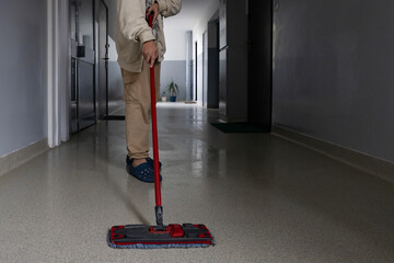 Person mopping a clean hallway in a modern building during daylight hours