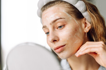 A close-up of a young woman's face with a mask reflected in a small mirror. A beautiful woman...