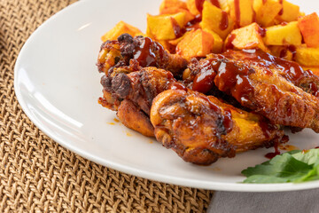 Bbq chicken wings with fried potato chunks and sauce