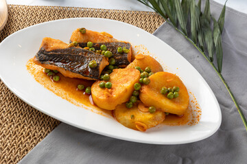 Baked fish fillets with potatoes, peas, and rich sauce