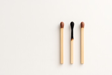 Three matchsticks on white background with center match burnt out symbolizing burnout and exhaustion. Represents emotional physical fatigue stress overload and reaching breaking point in work life..