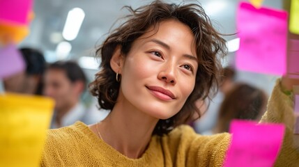 Woman engaging in collaborative brainstorming session with colorful sticky notes in modern office environment