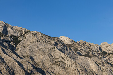 Gray rocks with small vegetation against the sky. Mountain landscape, Croatia. copy space