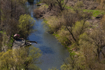 Tranquil river bends through lush greenery in a serene natural setting during early spring
