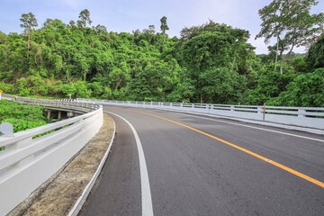 Fototapeta premium Road with a white railing on the side and trees in the background