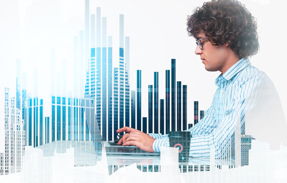 Focused young man typing on laptop, double exposure with cityscape and bar graph elements on white background, representing business and data analysis