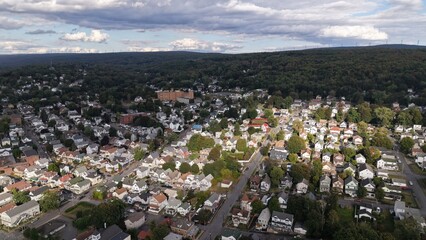 Aerial view of houses nestled closely together under a sky streaked with dramatic clouds, hinting at the city's embrace by nature, Carbondale, Pennsylvania, United States.