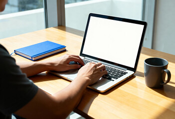 A person types on a laptop in a bright room.
