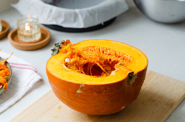 Close up of halved pumpkin on wooden cutting board ready for cooking