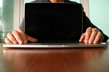 Businessman opening laptop on wooden desk