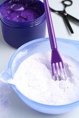 Hair care product for blonde hair and hairdresser's tools on white background, closeup