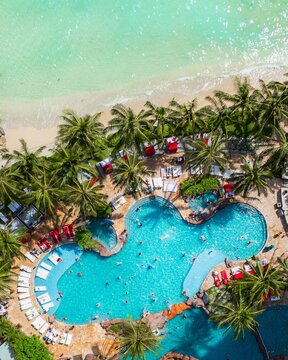 Aerial view of the Waikiki beach, where turquoise waters meet the sandy shore, fringed with palm trees and a vibrant pool teeming with life, Honolulu, Hawaii, United States.