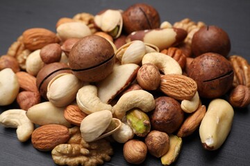 Mix of different nuts on black wooden table, closeup