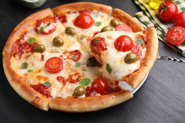 Taking piece of delicious pizza with cheese, tomatoes and olives at dark grey table, closeup