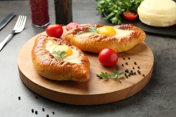 Tasty khachapuris with cheese and eggs served on grey table, closeup
