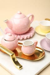 Tray with beautiful ceramic tea set for children on beige background, closeup