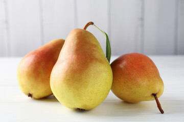Fresh ripe pears on white wooden table, closeup