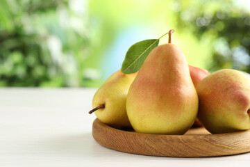 Fresh ripe pears on white wooden table outdoors, closeup. Space for text