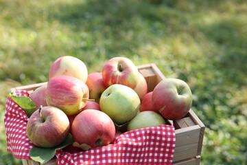 Fresh ripe apples in wooden crate outdoors, closeup. Space for text