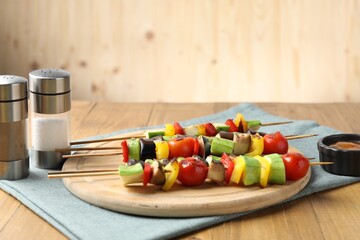 Vegetarian barbecue. Skewers with tasty grilled vegetables, spices and sauce on wooden table, closeup