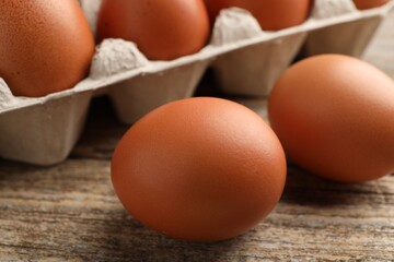 Raw chicken eggs on wooden table, closeup