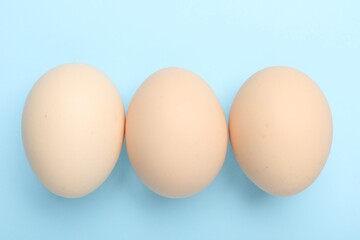 Fresh chicken eggs on light blue background, top view