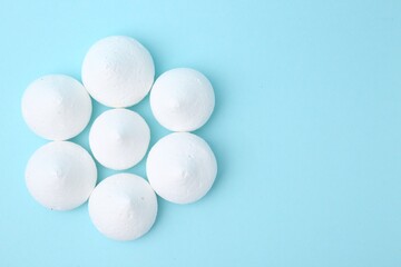 Yummy meringue cookies on light blue background, flat lay. Space for text