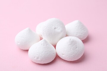 Many yummy meringue cookies on pink background, closeup