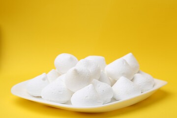 Yummy meringue cookies on yellow background, closeup