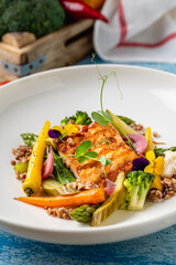 Seared salmon fillet served with grains and seasonal vegetables