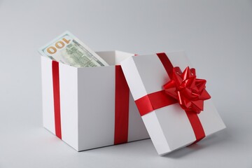Gift box with dollar banknotes on light grey background