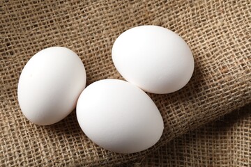 Raw chicken eggs on burlap cloth, above view