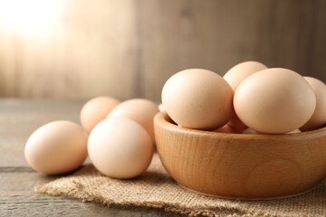 Raw chicken eggs in bowl on wooden table, closeup