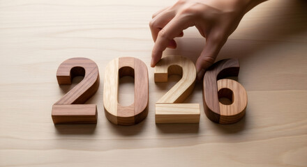 Person hand placing wooden number six to complete 2026. Concept of new year, planning, goal setting, and future.