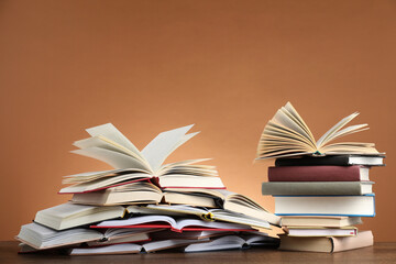 Many books on table against brown background. Space for text