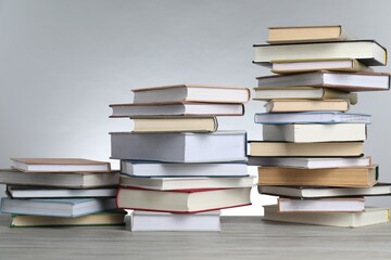 Many stacked books on table against light grey background