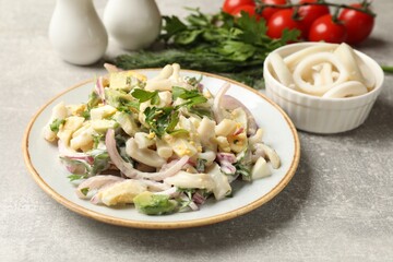 Tasty salad with squid rings, onion and eggs served on light grey table, closeup
