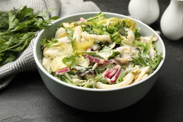 Tasty salad with squid rings, onion and eggs served on black table, closeup