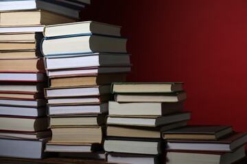 Many books on table against red background, closeup