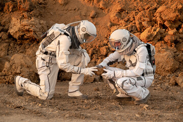 Explorers in astronaut gear analyzing Martian ground samples during planetary exploration.