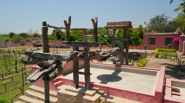 Aerial parallax shot of a rustic traditional wine press at Tambo de Tacama vineyard in Ica Peru with rows of grapevines and historic buildings