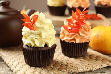 Delicious cupcakes with branches with red leaves on wooden table, closeup. Autumn atmosphere
