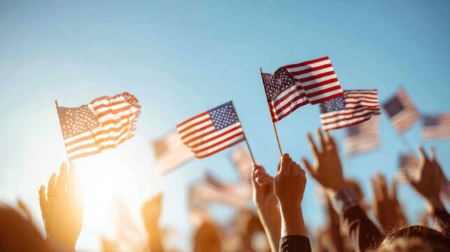 Crowd waves small American flags during national celebration at sunset near a vibrant sky