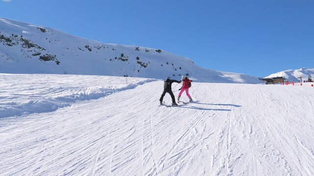 Experienced ski instructor guiding a beginner woman during her first lesson on a sunny day. Professional coach helping a female student learn how to ski on a gentle slope at a mountain resort